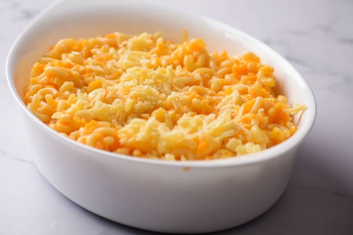 Carrot and cheddar macaroni and cheese in a white baking dish.