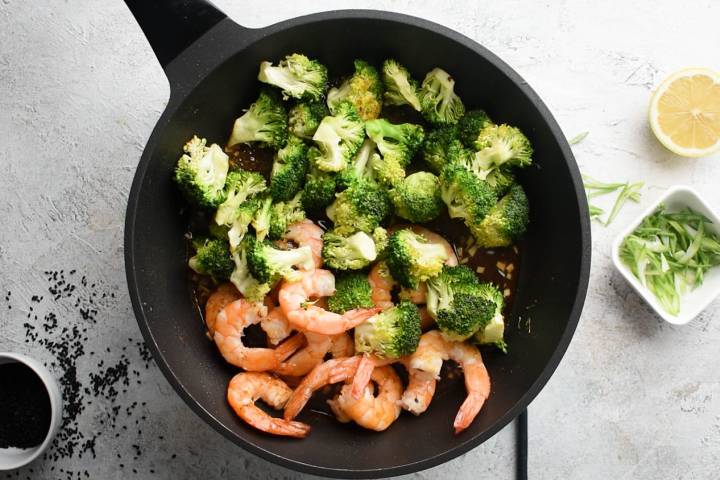 Firecracker sauce being added to shrimp and broccoli in a skillet.