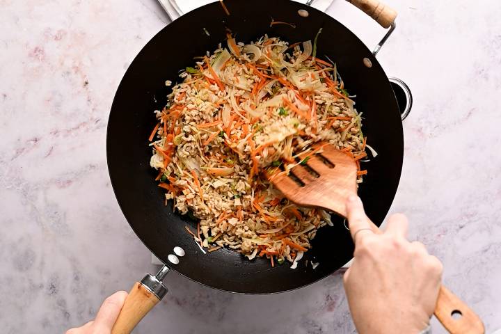 Brown rice and vegetables cooking in a wok.