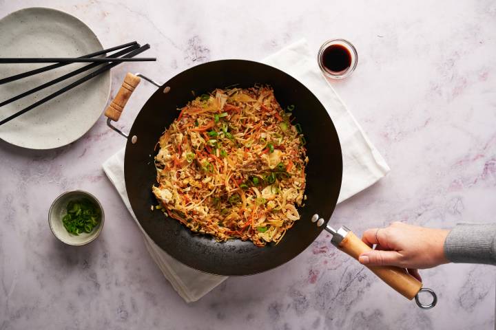 Healthy fried rice in a wok with green onions and soy sauce.