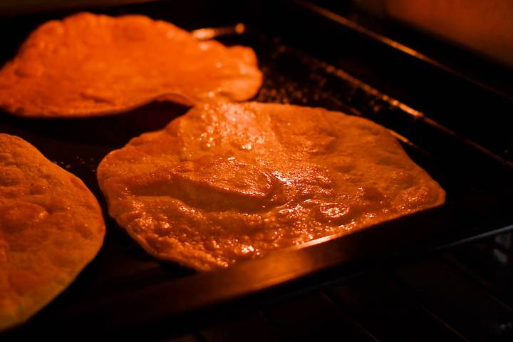 Tostada shells baking in the oven with small bubbles forming.
