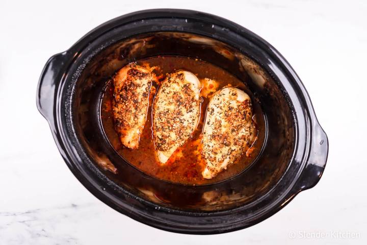 Chicken cooked in the slow cooker covered in buffalo sauce and herbs,