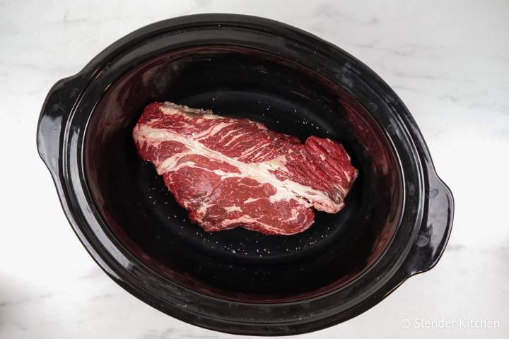 Lean beef in a slow cooker with salt and pepper.