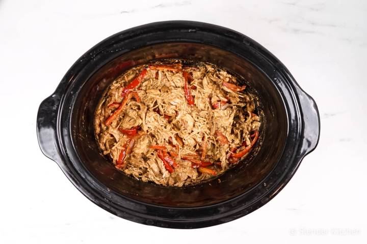 Shredded Thai Peanut chicken and red peppers in a crockpot.p