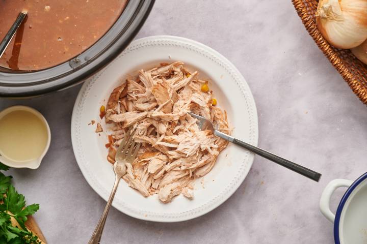 Healthy Taco Soup Shredded chicken on a plate next to a pot of taco soup.