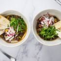Vegetarian tortilla soup with radishes and cilantro on top with crispy tortilla strips.