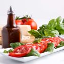 Balsamic vinaigrette in a glass jar with a tomato and basil salad.