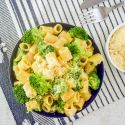 Broccoli pasta in a bowl with creamy parmesan sauce and Parmesan cheese on the side.