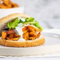 Buffalo chicken sandwich with blue cheese dressing on a bun with lettuce.