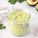 Creamy avocado dressing made with avocado, Greek yogurt, cilantro, lime juice, and garlic in a small glass jar.
