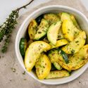 Sauteed zucchini and summer squash with fresh thyme and garlic in a bowl.