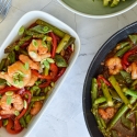 Honey garlic shrimp stir fry on a plate with asparagus, snap peas, red peppers, and stir fry sauce.