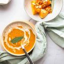 Slow cooker butternut squash soup in two bowls with a sage leaf on top.