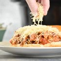 Slow cooker Tuscan turkey sloppy joes on a roll with shredded cheese.