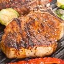 Grilled pork chops with southwestern seasoning on a grill with brussels sprouts and peppers.