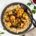 Thia baisl shrimp stir fry with zucchini, cooked shrimp, and brown rice in a bowl. 