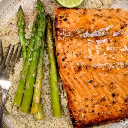Broiled salmon with honey garlic sauce on a plate with asparagus.
