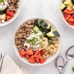 Chicken kofta bowls with tomatoes, cucumbers, hummus, and feta cheese in a bowl.