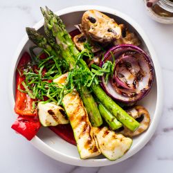 Grilled marinated vegetables with balsamic marinade in a white bowl.
