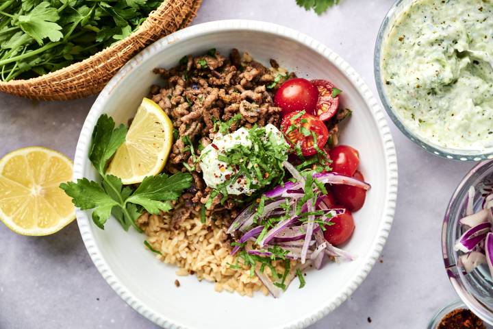 Kofta ground beef bowls with seasoned ground beef, brown rice, red onion, tomatoes, parsley, and cherry tomatoes.