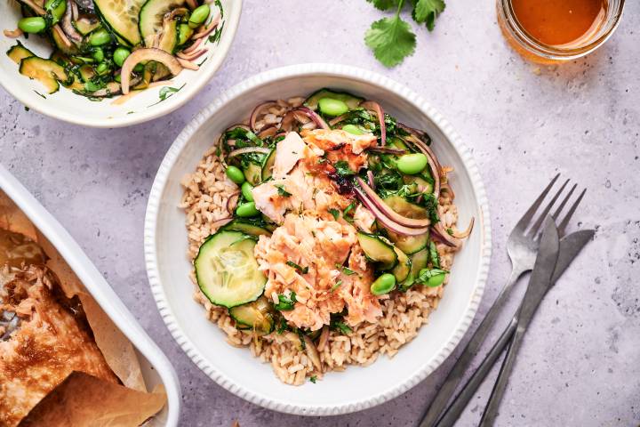 Salmon rice bowls with Asian salmon, cucumbers, edamame, red onion, herbs, and cooked brown rice.