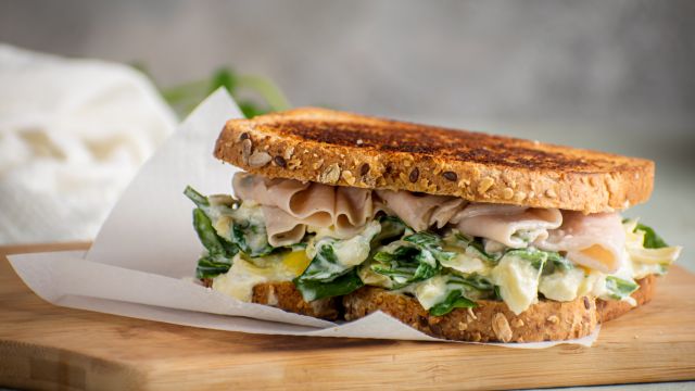 Spinach and artichoke grilled cheese sandwich with turkey breast on sliced wheat bread.
