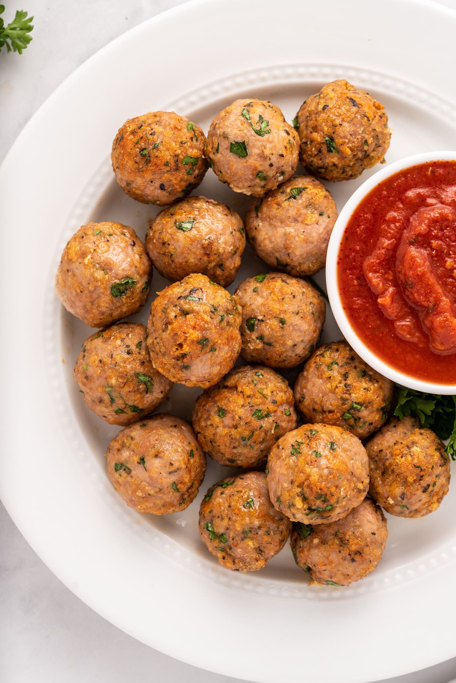 Easy turkey meatballs served on a plate with a small bowl of marinara sauce.