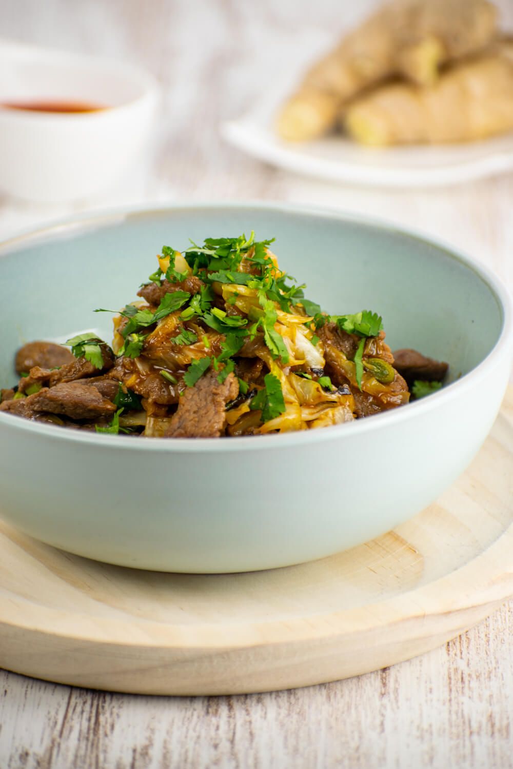 Moo shu stir fry with beef, cabbage, and green onions in a bowl with a spoon.