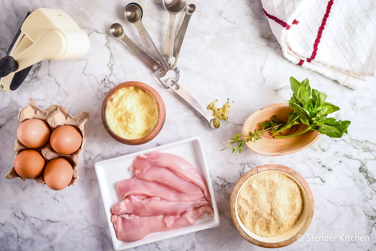 Ingredients to make Parmesan Crusted Chicken including cheese, egg whites, chicken breast, basil, and oregano.