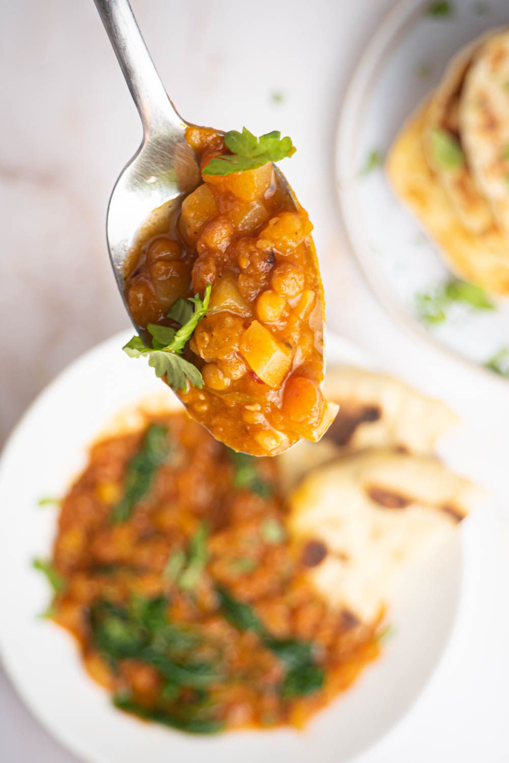 Madras curry lentils in a bowl with potatoes, spinach, and Naan bread.