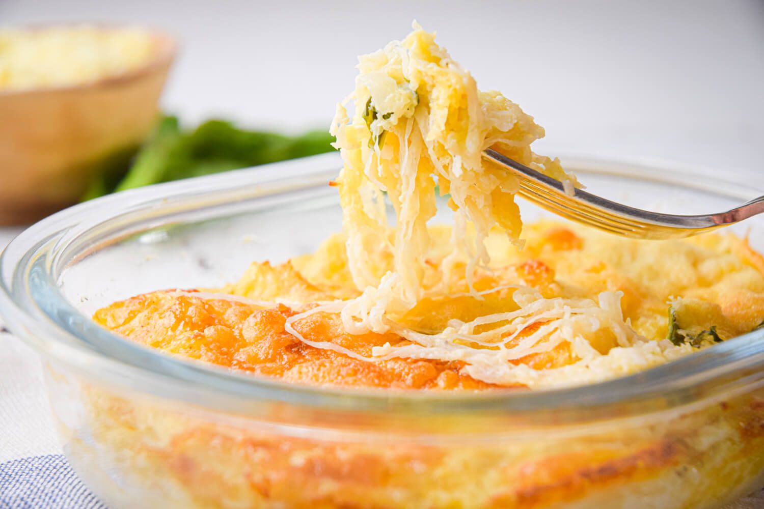 Au gratin with spaghetti squash, basil, garlic, onions, and melted cheese in a baking dish.