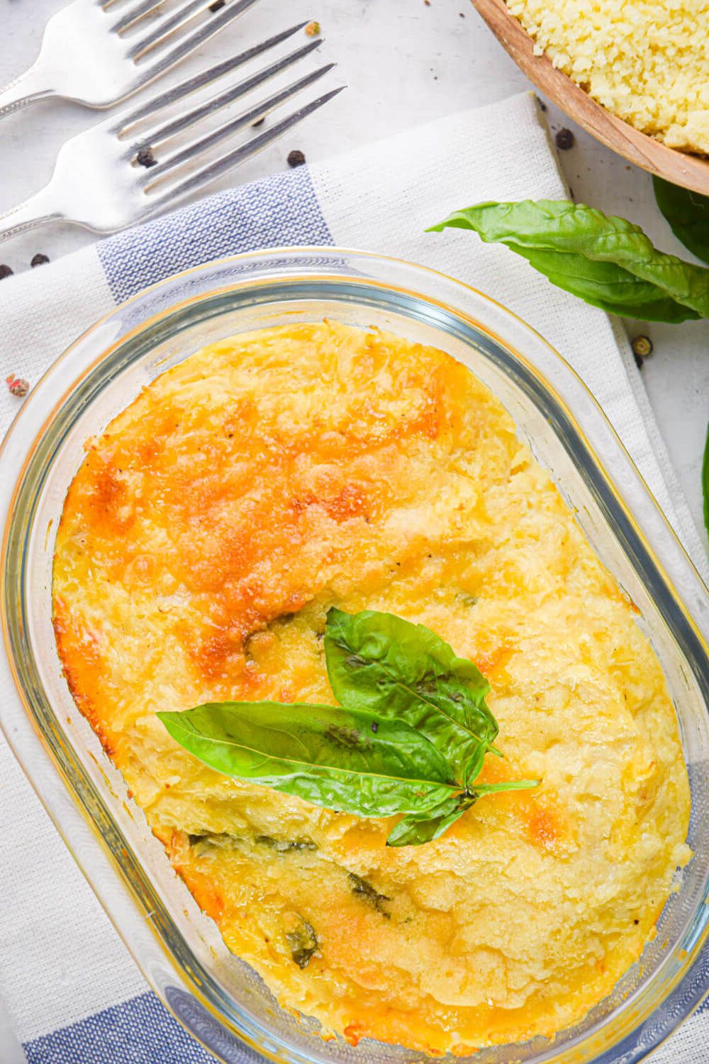 Spaghetti squash au gratin with fresh Parmesan and basil in a dish with two forks.
