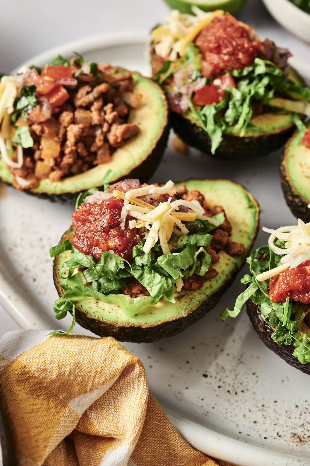 A plate featuring four stuffed avocados, each filled with a colorful mixture of ingredients, garnished for presentation.
