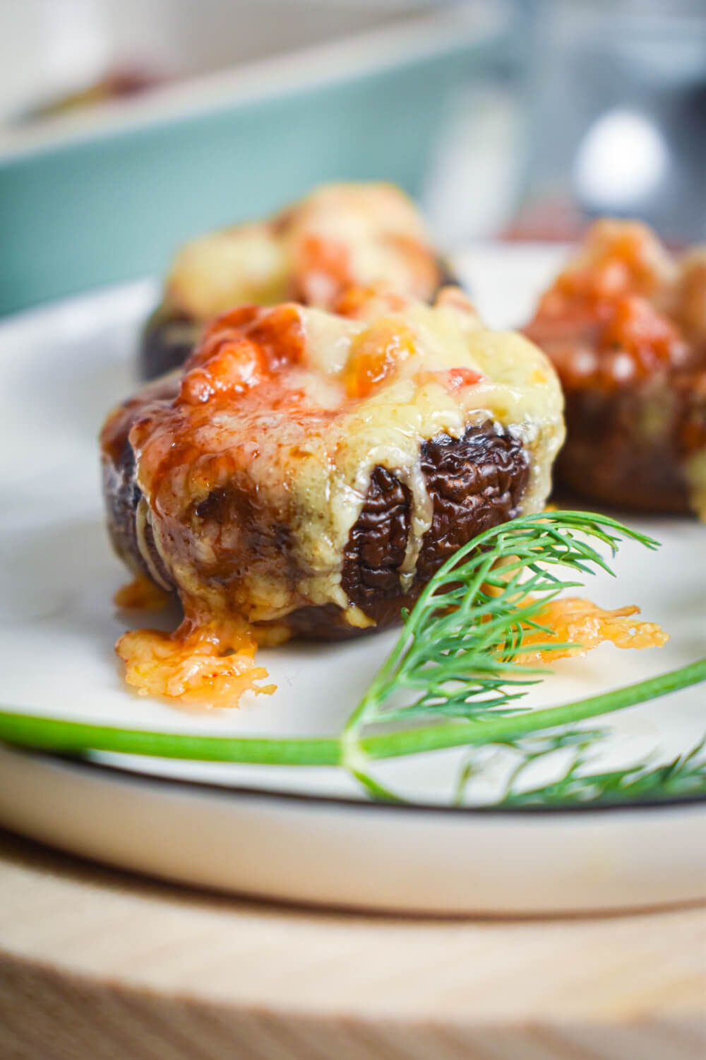 Mexican stuffed portabella mushrooms on a plate with melted cheese and enchilada sauce.