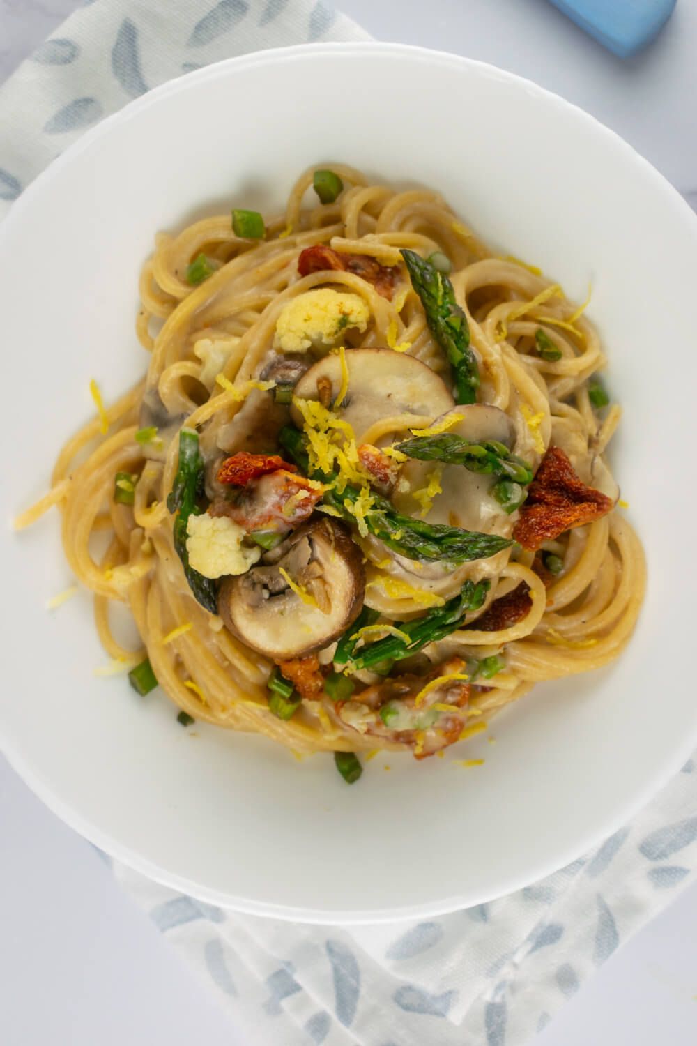 Alfredo with vegetables in a bowl with a creamy alfredo sauce, lemon, and vegetables.