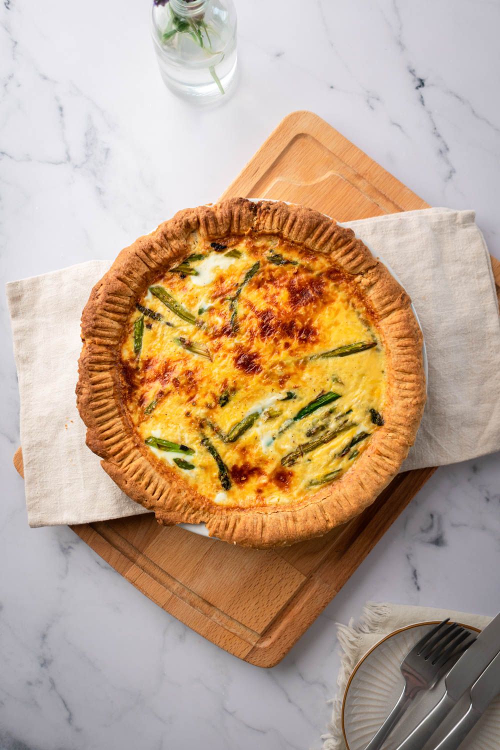 Asparagus and egg quiche with a golden brown crust, asparagus spears, and melted cheese.