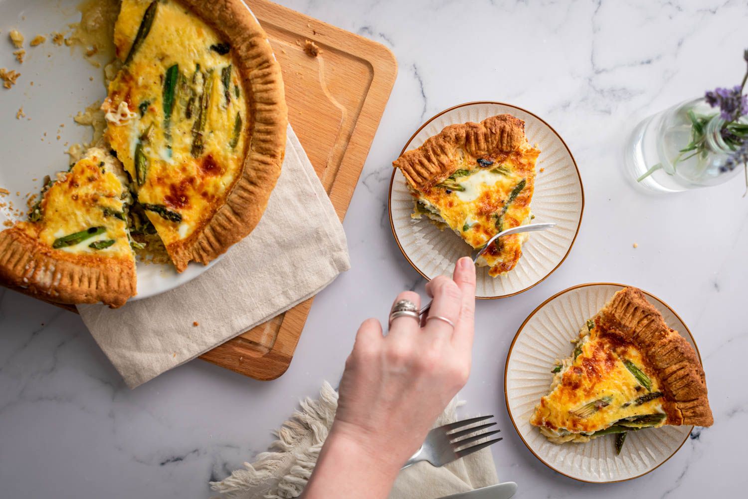 Quiche with asparagus, eggs, and cheese cut into slices and served on two plates.