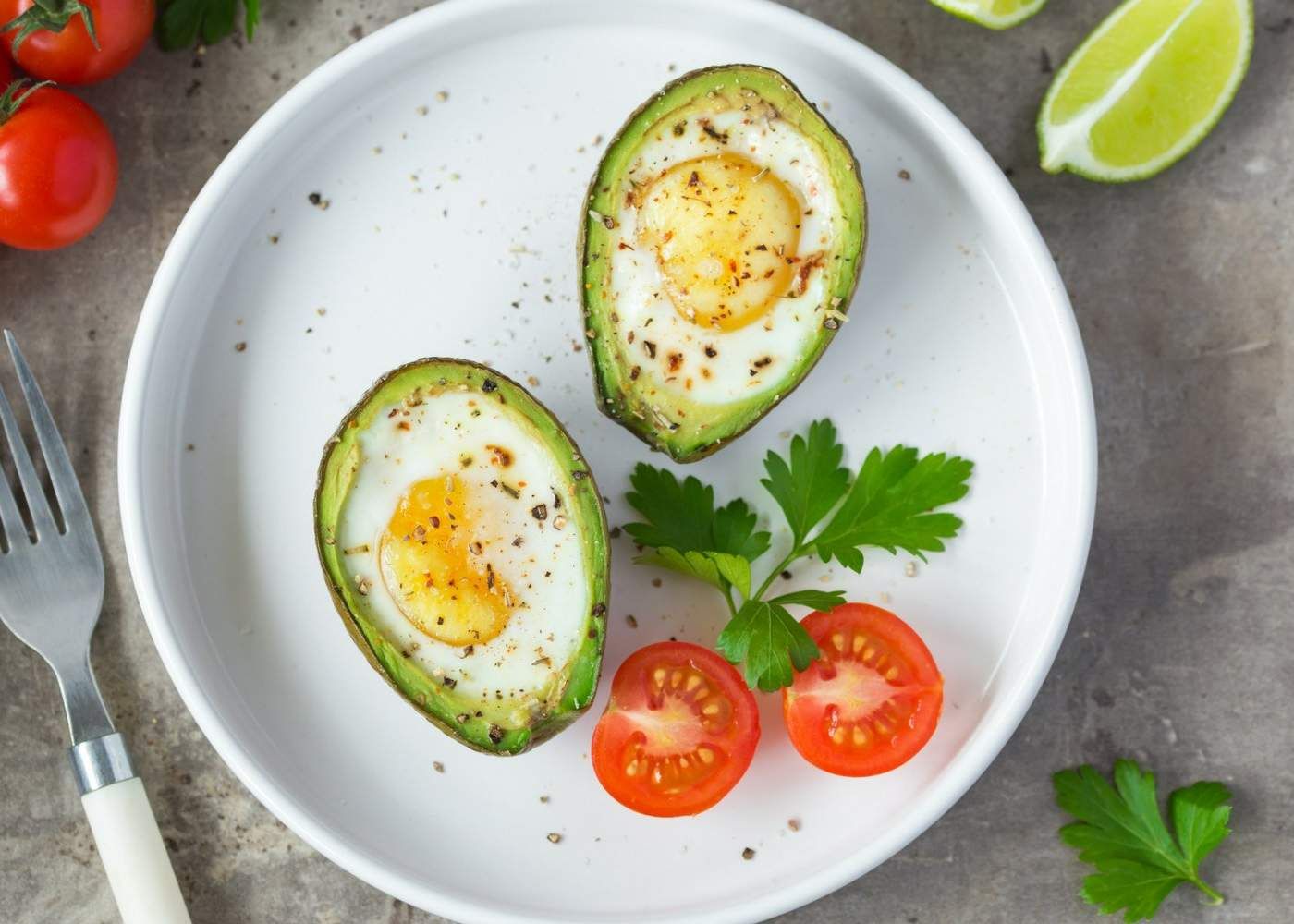Egg recipe for avocado baked eggs with tomatoes and fresh herbs.