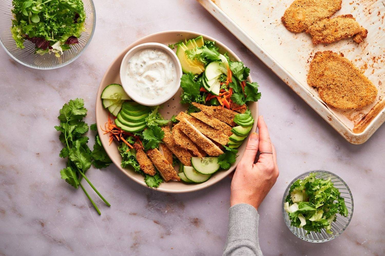Chicken cutlets served with salad and dipping sauce on a plate. 