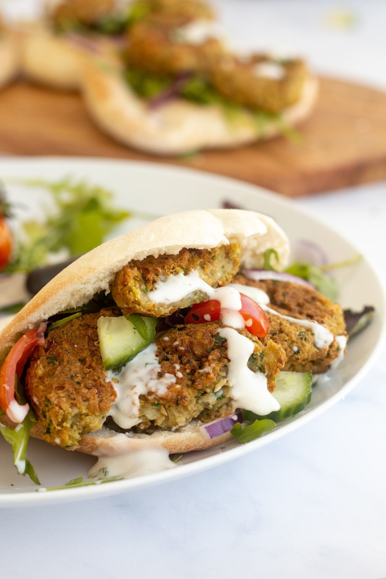 Homemade baked falafel served in a pita with cucumbers, tomatoes, and tahini.