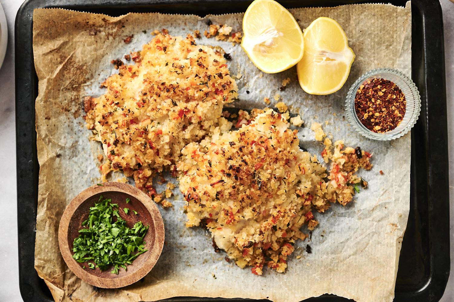 Baked haddock with seafood stuffing on a baking sheet with parsely and lemon.