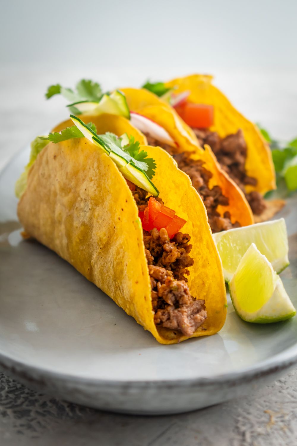 Baked taco shells with crispy browned edges and filled with taco meat, tomatoes, avocado, and cilantro.