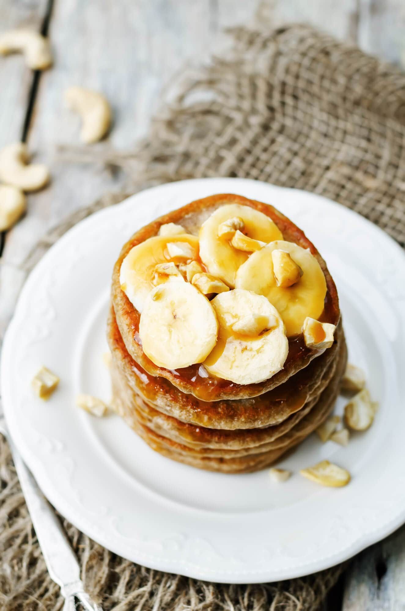Banana Protein Pancakes on a plate with sliced bananas and cashews.