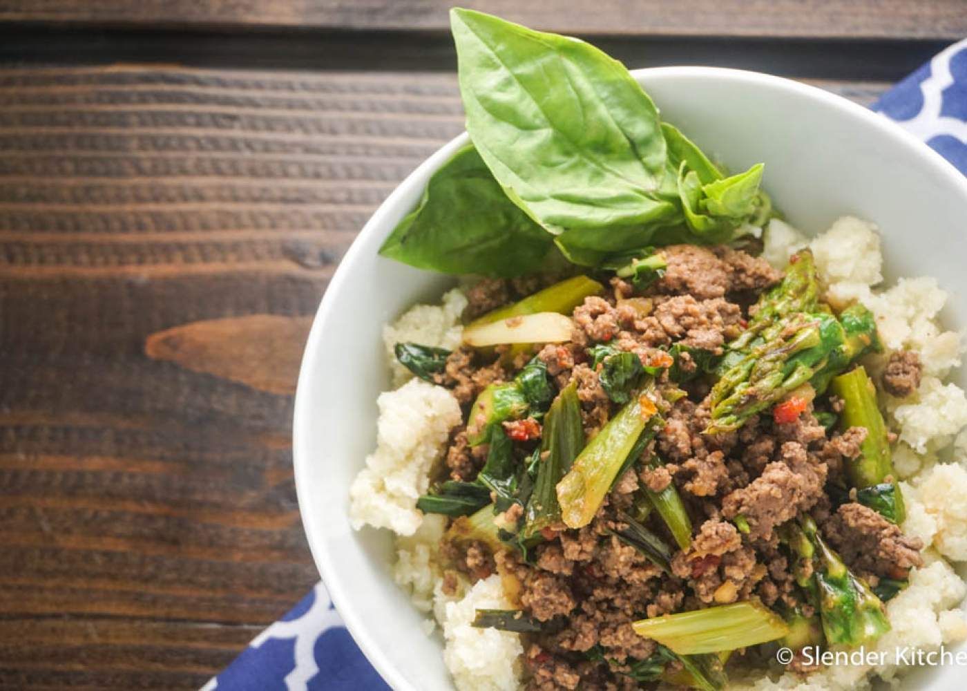Thai Basil Ground Beef in a bowl with fresh basil and a wooden background.