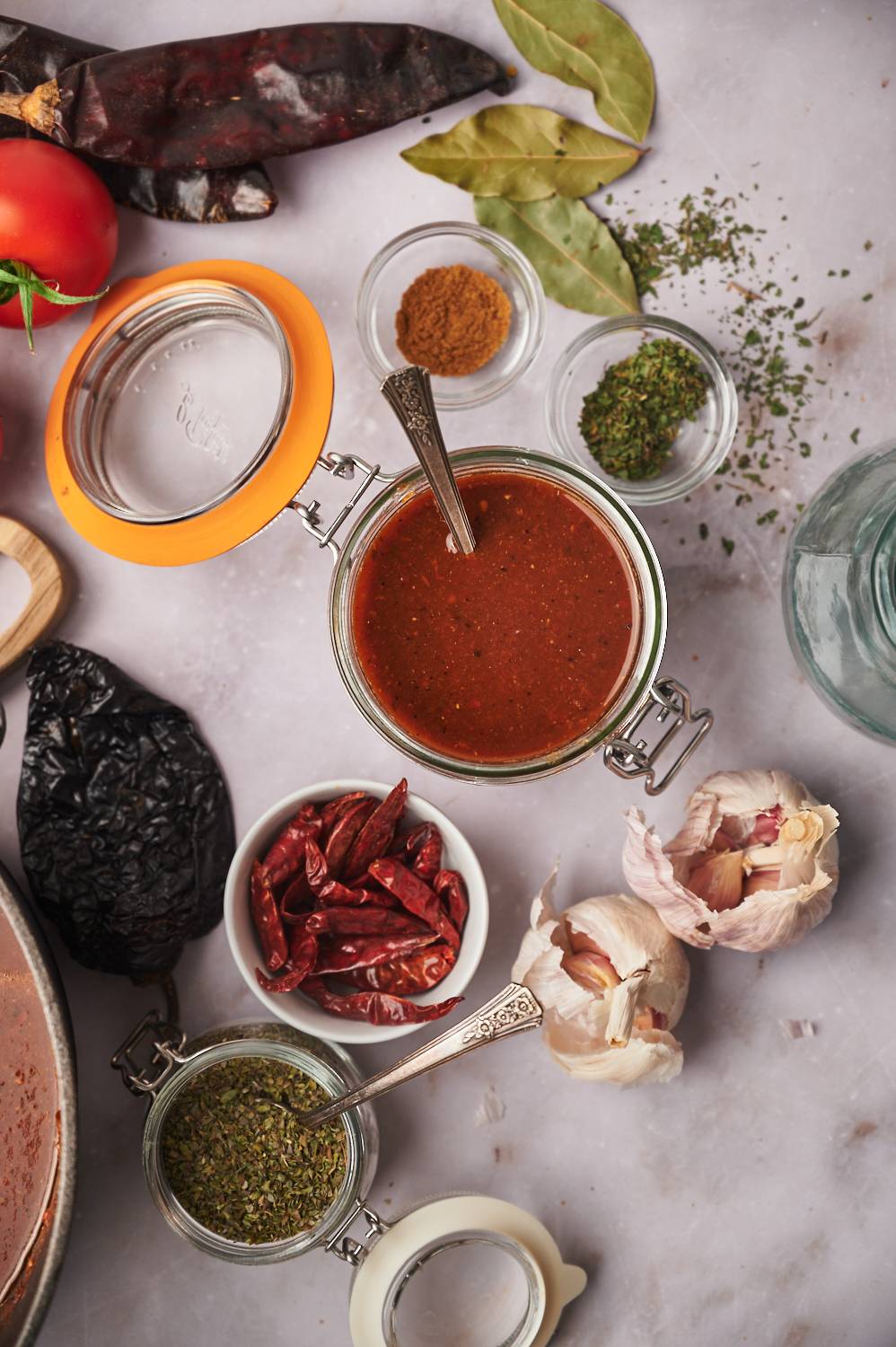 Birria sauce in a jar with dried chilie peppers and spices on the side.