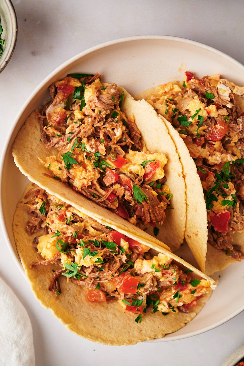 Beef machaca with scrambled eggs served in corn tortillas with cilantro.