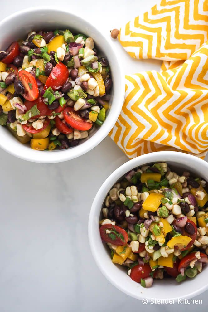 Black bean and corn salad with tomatoes, cilantro, and lime dressing in two bowls.