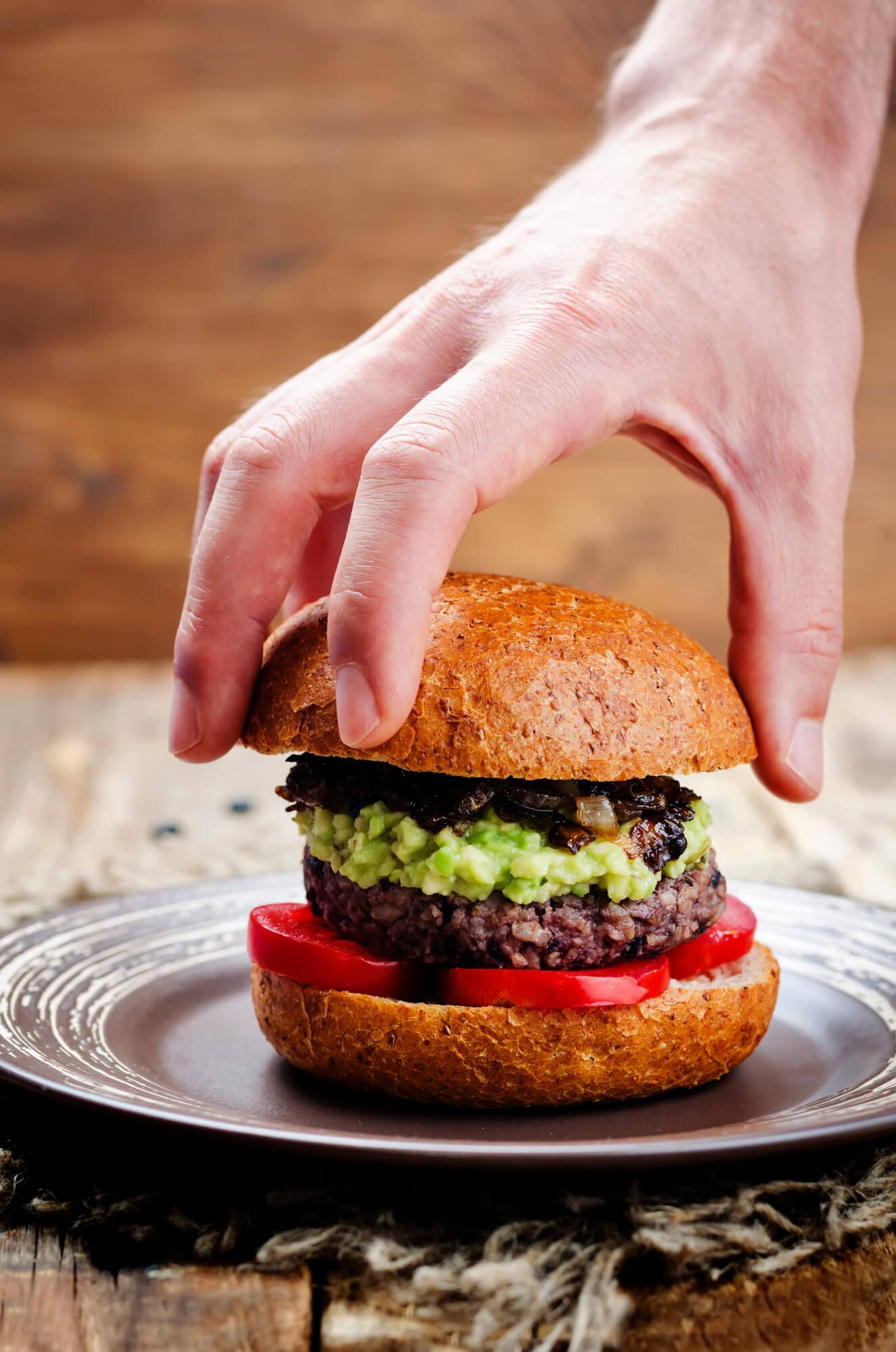 Salsa black bean burgers on a hamburger bun with avocado, tomatoes, and grilled onions.