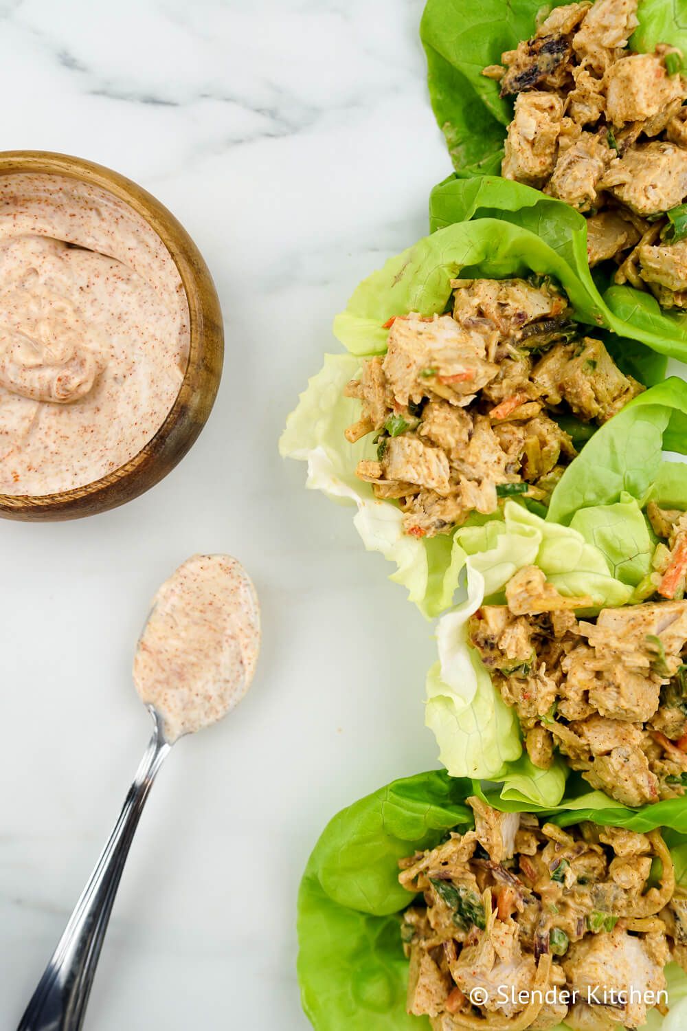 Healthy Spicy Chicken Salad in butter lettuce on white background.