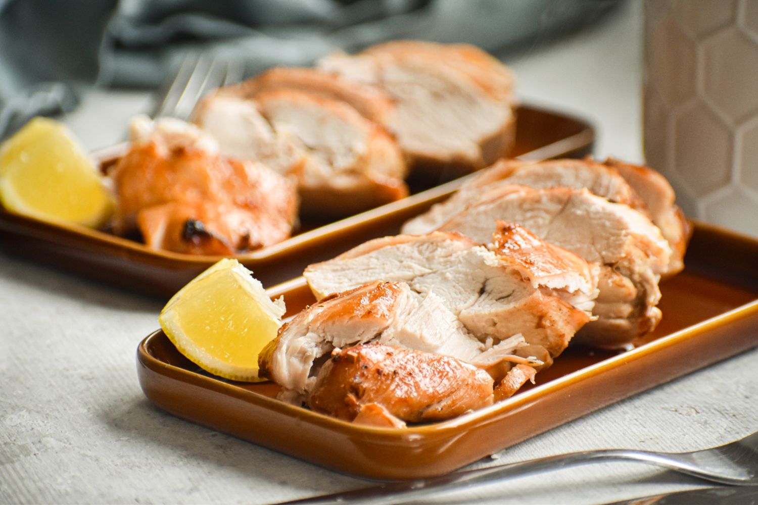 Chicken breasts with a brown sugar and garlic coating sliced on two plates.